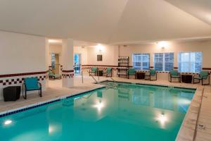 a pool with chairs and tables in a hotel at Residence Inn by Marriott Rogers in Rogers