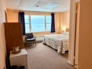 a bedroom with a bed and a window and a chair at The Shoreline Inn in Grand Marais