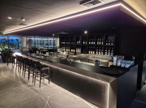 a bar with bar stools and bottles of wine at Porto 2 live in Porto De Galinhas