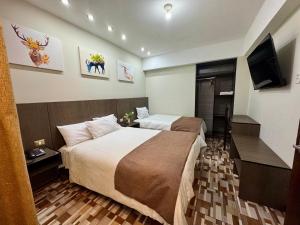 a hotel room with two beds and a flat screen tv at Hotel Coronado in Tacna