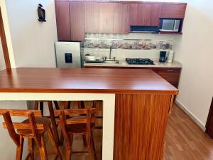 a kitchen with a counter with chairs and a refrigerator at Departamento acogedor, moderno y céntrico in Apizaco