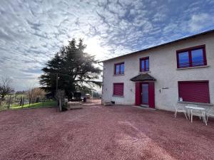 a white house with a red door and a yard at Le Pas Sans Peine in Le Cergne