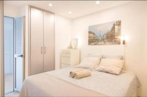a white bedroom with a bed and a painting on the wall at New Puerto Rico Terrace Swiming Pool in Mogán