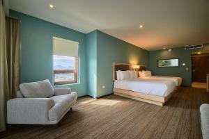 a bedroom with a bed and a chair and a window at Wyndham Garden Saltillo in Saltillo