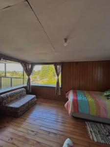 a bedroom with a bed and a couch and a window at Casona de Campo in Puerto Varas