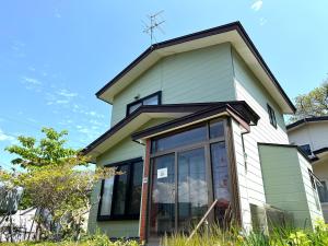 a green and white house with a large window at Local Stay Hakodate in Hakodate