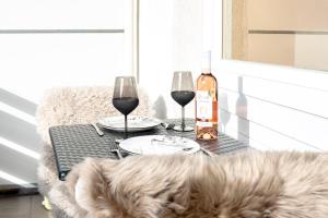a table with two wine glasses and a bottle of wine at Studio MORGINS avec piscine Gratuite in Morgins