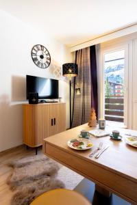 a living room with a table and a tv at Studio MORGINS avec piscine Gratuite in Morgins