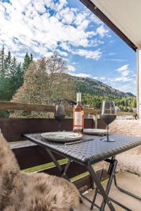 a table with a bottle of wine and two glasses at Studio MORGINS avec piscine Gratuite in Morgins