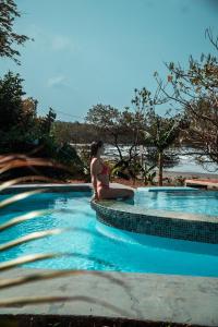 a woman in a bikini sitting next to a swimming pool at Hotel Bohemian Lagarto in Santa Cruz