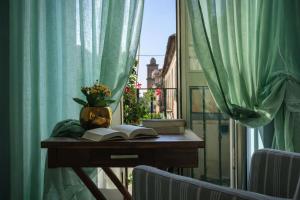 a table with books and a vase of flowers on a window at Maison Geraldine in Marcianise