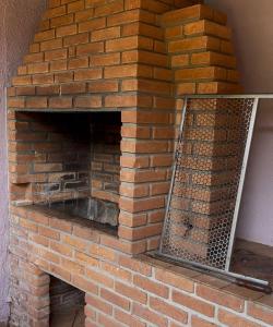 a brick fireplace with a metal grate on it at Chateau Magalhães in Itatiba