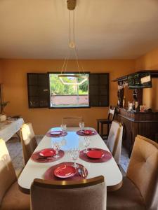 a dining room with a table with red plates and glasses at Espaço Sunshine in Saquarema