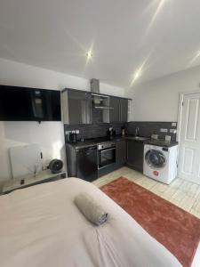 a room with a bed and a kitchen with a washing machine at Spacious Luxury 2bd with extra Private Studio Room in Catford