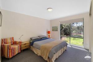 a bedroom with a bed and a chair and a window at The Ash, Sandy Point Stay 3 Pay 2 Winter Special in Sandy Point