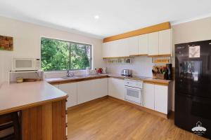a kitchen with white cabinets and a black refrigerator at The Ash, Sandy Point Stay 3 Pay 2 Winter Special in Sandy Point +4 photos