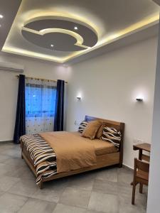 a bedroom with a large bed with a ceiling with a recessedigunigunigun at Résidence Prestige KGV 1er lot de 14 appartements meublés in Douala