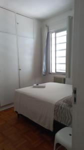a bedroom with a large white bed and a window at Quartos em Meireles Fortaleza in Fortaleza