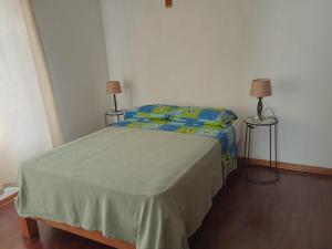 a bedroom with a bed with two lamps and two tables at KUSIHaus in Lima