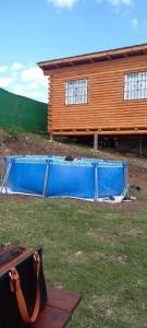 a blue swimming pool in front of a house at Los Espinillos Cabaña Exclusiva in Huerta Grande