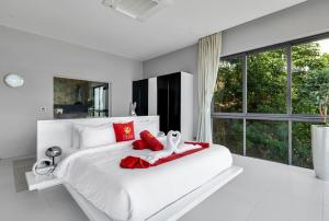 a white bedroom with a large white bed with red pillows at STK Villa Samui Paradise Awaits in Nathon Bay +67 photos