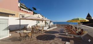 a group of people sitting on a patio with chairs and umbrellas at Residenza Sole Amalfi in Amalfi