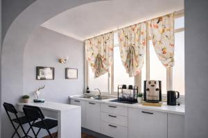 a kitchen with a sink and a window with curtains at Maison Geraldine in Marcianise