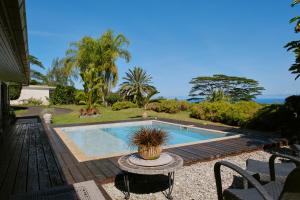 a swimming pool in a yard with a table and chairs at Enjoy Camanukea Lodge in Mahina