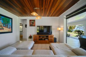 a living room with two couches and a flat screen tv at Enjoy Camanukea Lodge in Mahina