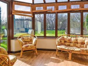 a living room with two chairs and windows at Bridge House in Overseal