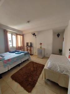 a bedroom with two beds and a rug at Pousada recanto das ondas in Macaé +22 photos