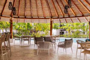 a restaurant with tables and chairs and a pool at Palmas de Tamarindo Resort, 304E in Guanacaste