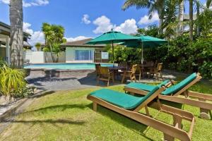 a patio with chairs and umbrellas next to a pool at Takapuna Motor Lodge in Auckland