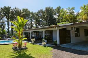 a house with a palm tree next to a pool at Enjoy Camanukea Lodge in Mahina