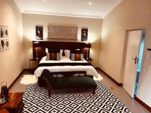 a bedroom with a large bed and a black and white rug at Haze Inn Cottages Crowned in Henburg Park