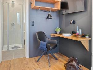 a desk and a chair in a room with a shower at City Pension Heide in Heide