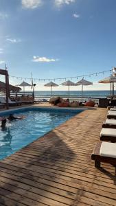 a swimming pool next to a beach with umbrellas at The Point Mancora Beach - Hostel Juvenil de Fiesta in Máncora
