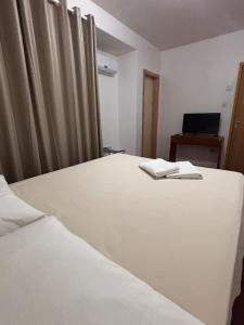 ein weißes Bett in einem Zimmer mit einem Laptop in der Unterkunft Osório Hotel in Osório