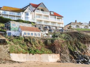 a building on top of a cliff next to the beach at Gilly's Cottage in Kingsbridge