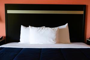 a bed with a black headboard and white pillows at Elkton Lodge - Newark - Elkton University Gateway in Elkton +8 photos