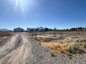 a dirt road with a blue house in the distance at Death Valley PrairieFire 3bd 2ba Home w Kitchen in Pahrump