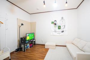 a living room with a white couch and a tv at Traditional Korean houses Stay Yeon in Busan