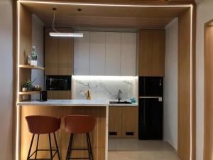 a kitchen with two bar stools and a black refrigerator at Light Star Villa in Kuta Lombok
