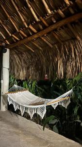 a hammock in a straw roofed room with plants at Cabaña la Industrial in Coveñas