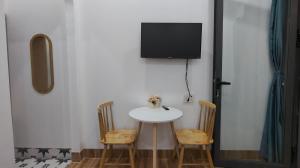 a small table with two chairs and a tv on a wall at Sơn Hà homestay in Ấp Bình Hưng