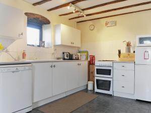 a kitchen with white cabinets and white appliances at Granary Barn in Marros