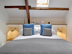 a bedroom with a large bed with blue pillows at Granary Barn in Marros