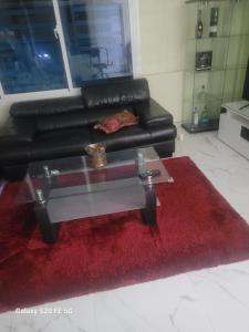 a living room with a red rug and a black couch at " Bienvenido a casa " in San Pedro de Macorís