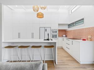 a kitchen with white cabinets and bar stools at The Eddy Escape in Kingscliff