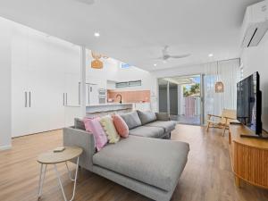 a living room with a gray couch and a kitchen at The Eddy Escape in Kingscliff